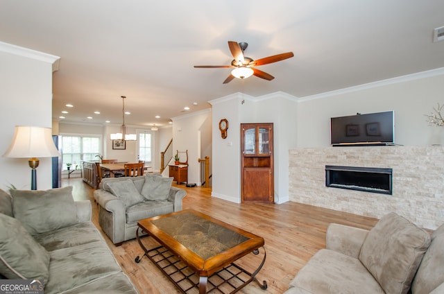 living area featuring ornamental molding, recessed lighting, a fireplace, light wood finished floors, and ceiling fan with notable chandelier