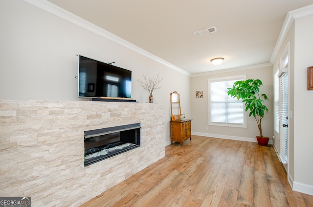 living room featuring baseboards, ornamental molding, a fireplace, visible vents, and wood finished floors