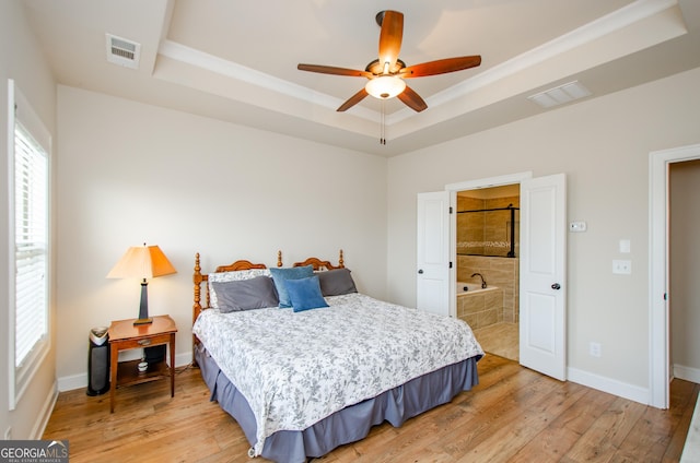 bedroom featuring a tray ceiling, light wood finished floors, and visible vents