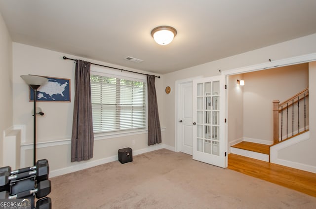interior space featuring visible vents, baseboards, carpet floors, stairs, and french doors