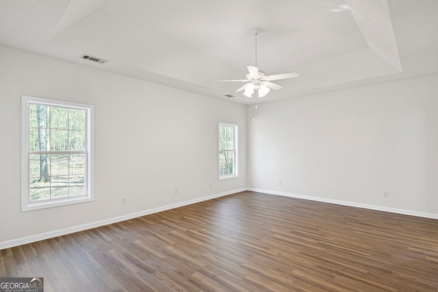 185 Cold Harbor Ct, Sharpsburg, GA 30277 - spare room with baseboards, dark wood finished floors, visible vents, a tray ceiling, and ceiling fan