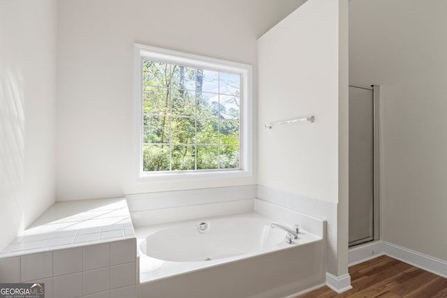 185 Cold Harbor Ct, Sharpsburg, GA 30277 - bathroom featuring a bath, wood finished floors, and a stall shower