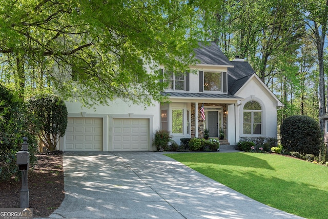 view of front of property with stucco siding, a standing seam roof, concrete driveway, a front yard, and a shingled roof