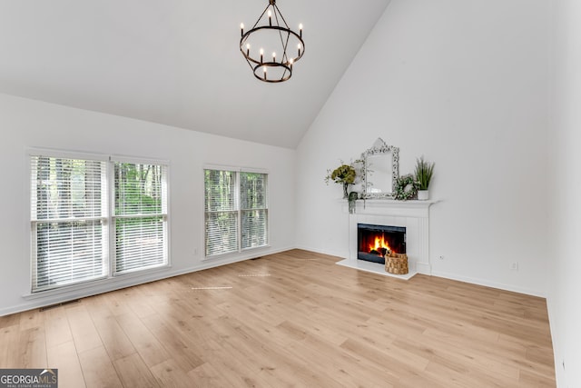 unfurnished living room featuring a chandelier, a fireplace, light wood-style floors, high vaulted ceiling, and baseboards