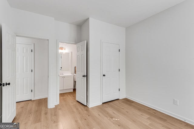 unfurnished bedroom featuring light wood-type flooring, baseboards, and ensuite bathroom