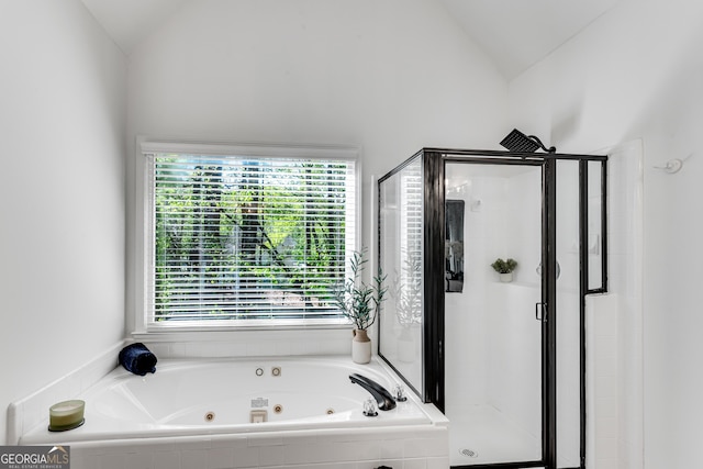 bathroom featuring vaulted ceiling, a jetted tub, and a shower stall