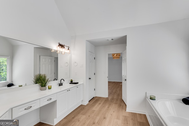 full bathroom with wood finished floors, vanity, vaulted ceiling, a bath, and baseboards