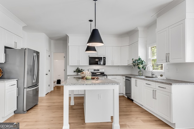 kitchen featuring a sink, appliances with stainless steel finishes, white cabinetry, light wood finished floors, and a center island