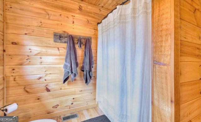 bathroom featuring a shower with curtain, visible vents, wood ceiling, wood finished floors, and wood walls