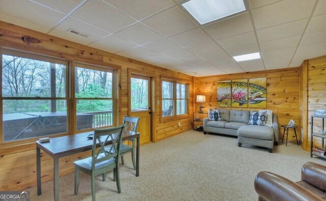 living room with carpet floors, wood walls, visible vents, and a wealth of natural light