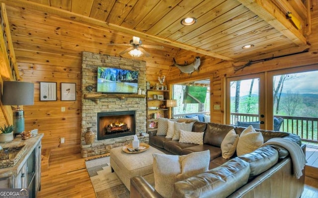 living room featuring a stone fireplace, recessed lighting, wooden walls, hardwood / wood-style floors, and wooden ceiling