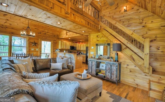 living area featuring light wood-style flooring, wood ceiling, wood walls, lofted ceiling, and a notable chandelier