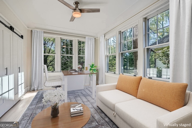 sunroom / solarium with a barn door, wood finished floors, and a healthy amount of sunlight