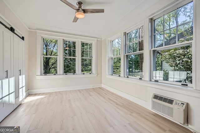 unfurnished sunroom with a barn door, baseboards, an AC wall unit, and wood finished floors