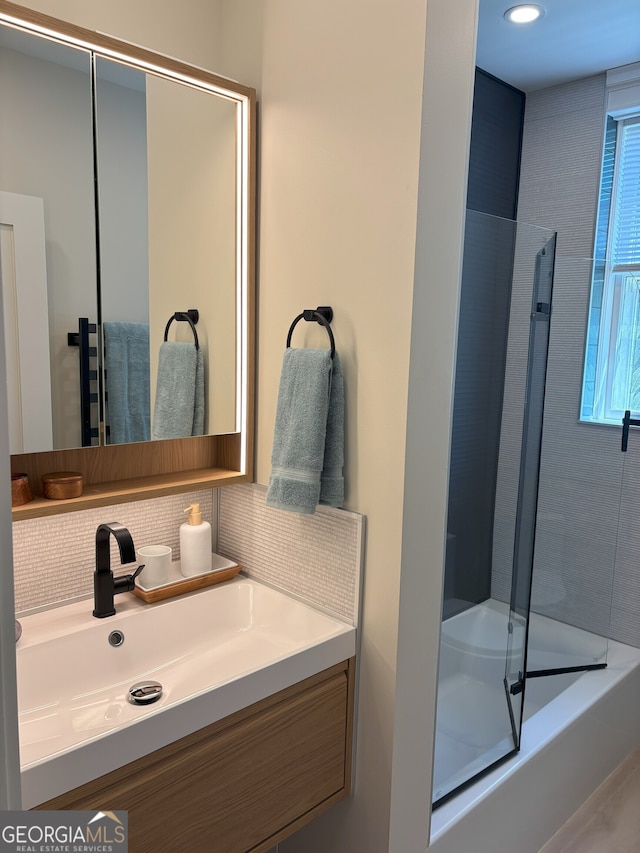 bathroom featuring shower / bath combination with glass door, vanity, and backsplash