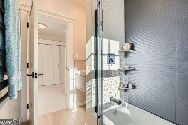full bath featuring washtub / shower combination and wood finished floors