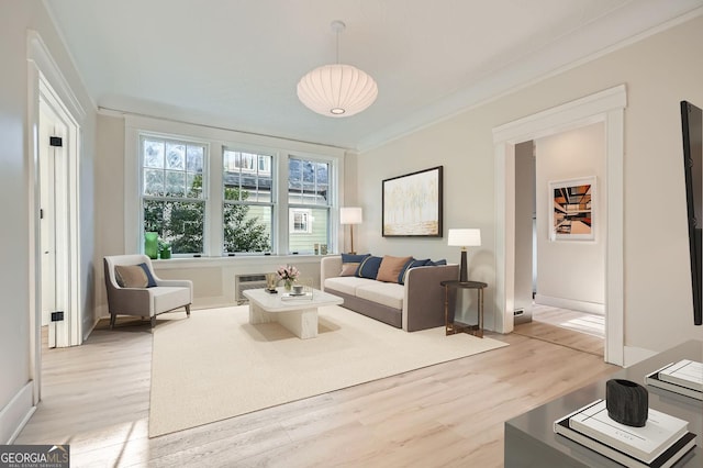 living room with light wood-type flooring, baseboards, and ornamental molding