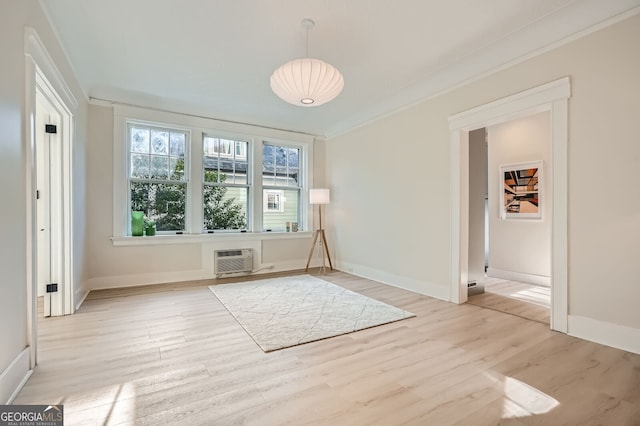 interior space featuring ornamental molding, light wood-style flooring, a wall mounted AC, and baseboards
