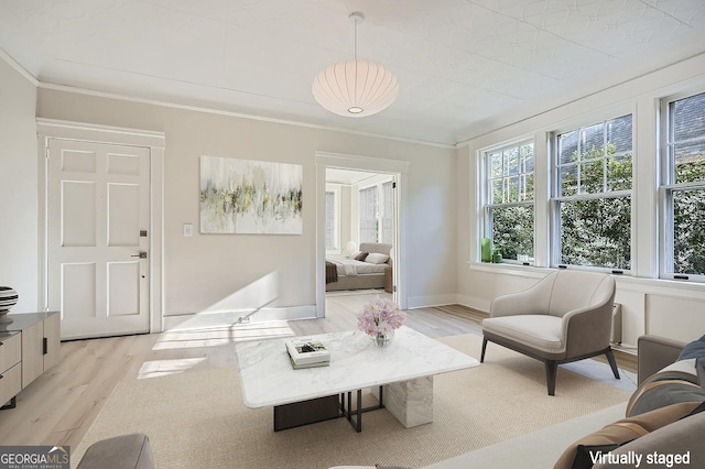 living area with light wood-type flooring, baseboards, and crown molding