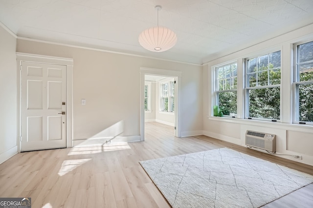 interior space featuring a wall unit AC, baseboards, ornamental molding, and wood finished floors