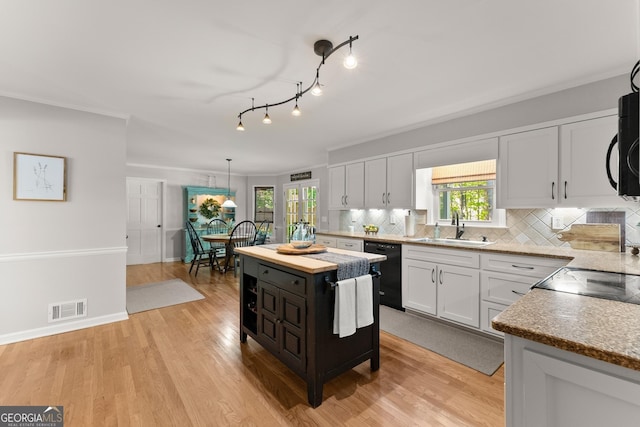 kitchen with a sink, black appliances, decorative backsplash, white cabinets, and visible vents