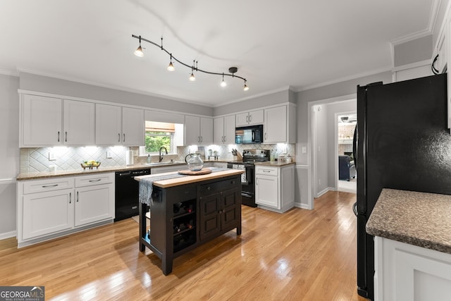 kitchen featuring tasteful backsplash, white cabinetry, a sink, and black appliances