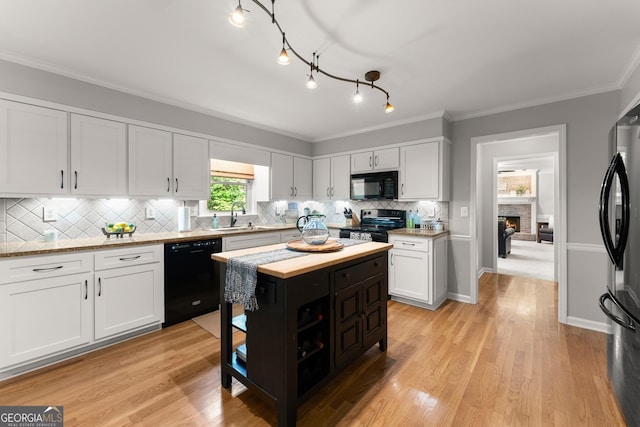 kitchen with white cabinets, tasteful backsplash, a sink, and black appliances