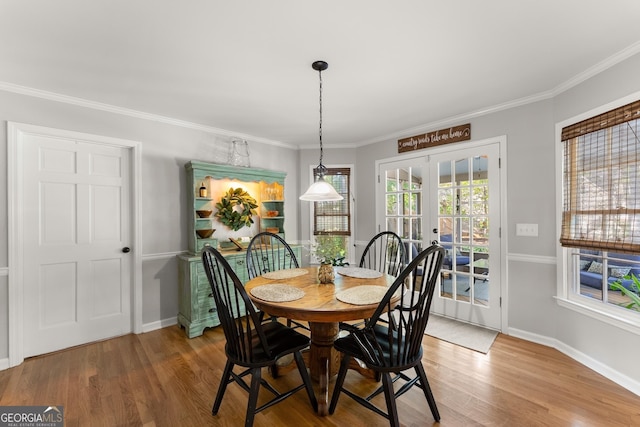 dining area featuring wood finished floors, baseboards, ornamental molding, and french doors
