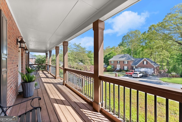 wooden deck featuring a porch and a lawn