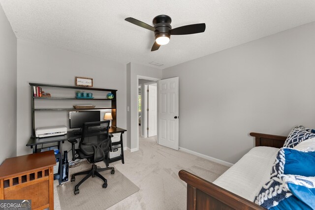 bedroom with light colored carpet, ceiling fan, baseboards, and a textured ceiling