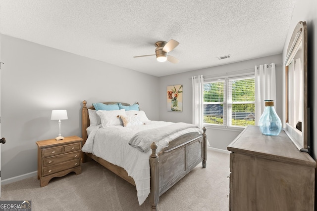 bedroom featuring light colored carpet, baseboards, a textured ceiling, and visible vents
