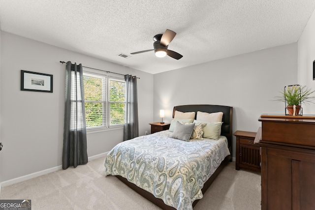 bedroom with a textured ceiling, ceiling fan, light carpet, baseboards, and visible vents