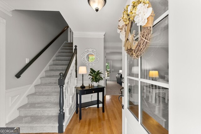 entrance foyer featuring wood finished floors, stairs, and ornamental molding