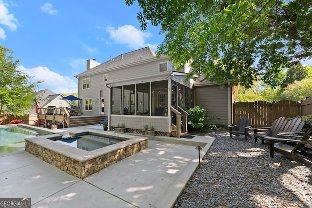 rear view of property featuring a fenced in pool, a gate, a wooden deck, a sunroom, and an in ground hot tub