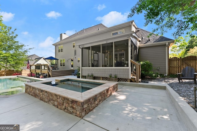 back of house with a fenced in pool, a wooden deck, a patio area, a sunroom, and an in ground hot tub