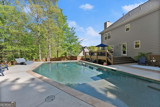pool featuring a wooden deck, a patio area, and fence