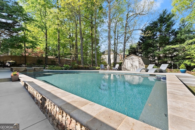 view of swimming pool featuring an outdoor structure, a storage unit, a fenced in pool, and fence