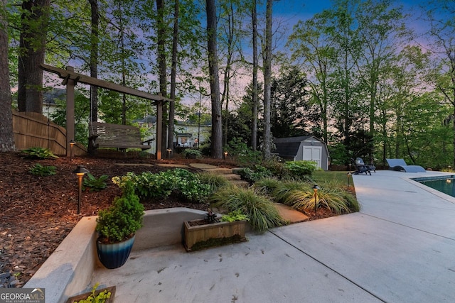 view of yard featuring fence, a swimming pool, an outbuilding, a patio, and a storage unit