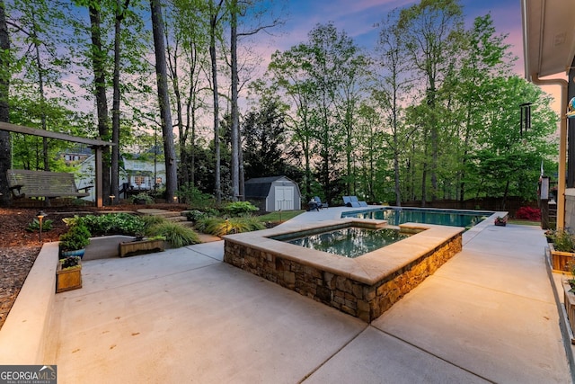pool at dusk featuring a patio, an outdoor structure, an outdoor pool, and a shed