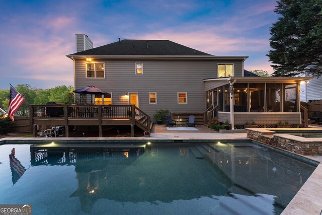 view of pool featuring stairway, fence, a patio, a wooden deck, and a sunroom