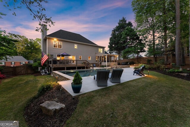 rear view of property with a patio area, a chimney, a deck, a fenced backyard, and a sunroom