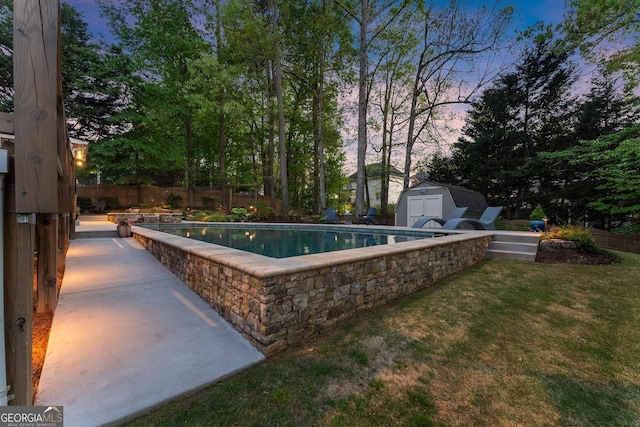 view of pool featuring a fenced in pool, fence, a storage shed, an outbuilding, and a lawn