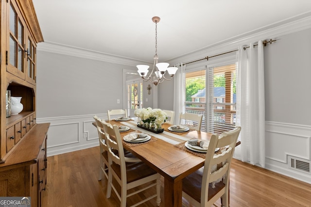 dining room featuring wainscoting, visible vents, and ornamental molding