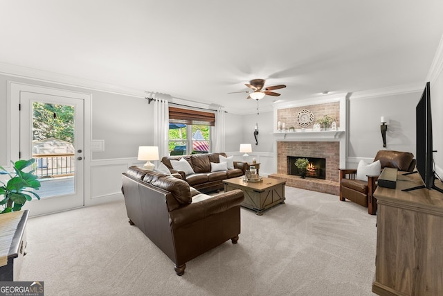 living room with a ceiling fan, ornamental molding, light colored carpet, and a brick fireplace