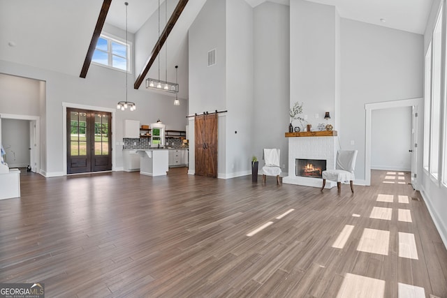 1001 Sugar Hill Way, Buckhead, GA 30625 - unfurnished living room featuring a barn door, a fireplace, a wealth of natural light, and high vaulted ceiling