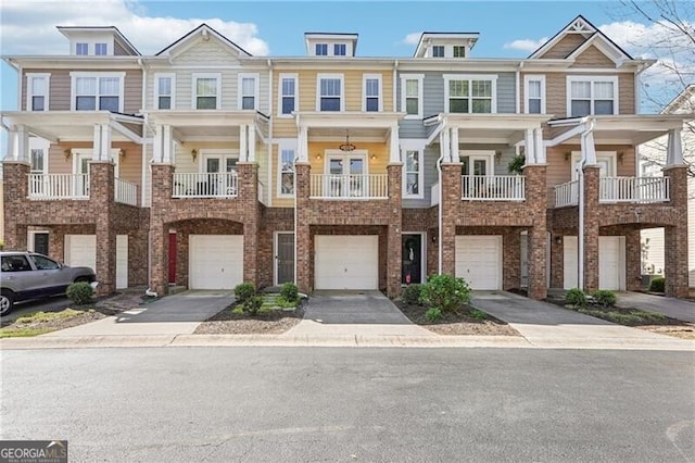 townhome / multi-family property with a garage, driveway, and brick siding