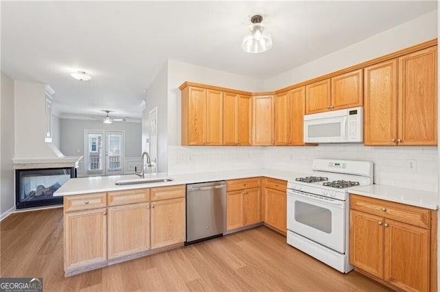 kitchen with a sink, light wood-style flooring, tasteful backsplash, and white appliances