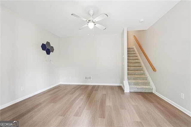 unfurnished living room featuring visible vents, baseboards, a ceiling fan, stairway, and wood finished floors