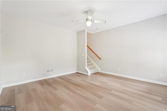 spare room with visible vents, baseboards, a ceiling fan, light wood-style floors, and stairs