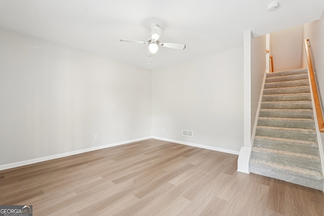 staircase with wood finished floors, baseboards, a ceiling fan, and visible vents